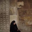 Een gesluierde dame en een stenen leeuw bij de poort van de citadel van Aleppo