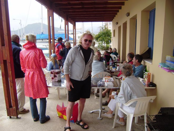 De zondagmiddagse zeilersbarbecue in de haven. Op de voorgrond Allen, de Britse bewoner van een Turkse gulet die de Zweedse vlag voert. Links van hem in regenjas staat Ans met Geert