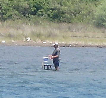Marmaris. Op de zandplaat bij het moerasje naast Pupa Yacht Hotel staat een man op krab te vissen
