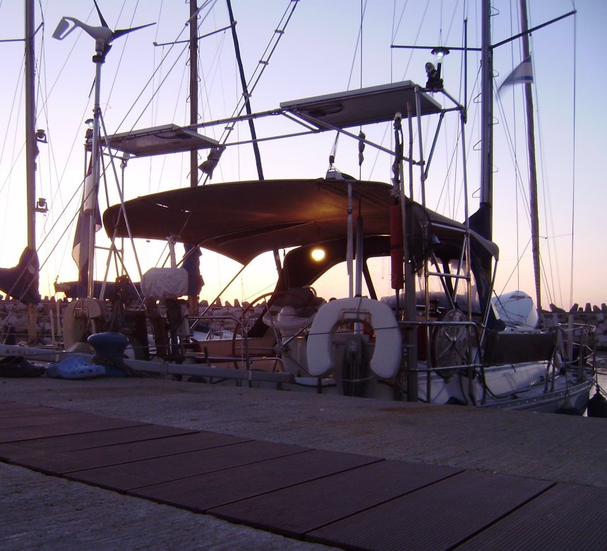 De avond valt in Ashkelon. De bimini staat erop en zie, eronder brandt het Turkse lampje uit Fethiye. De goede waarnemer ziet ook de lichtjes van de solar-kabouters uit Malta