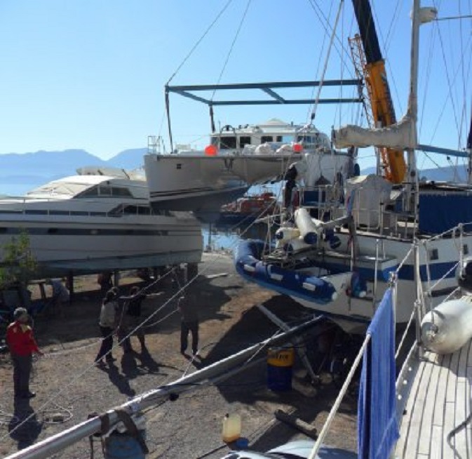De grote catamaran schuin voor ons wordt door een hijskraan opgehesen