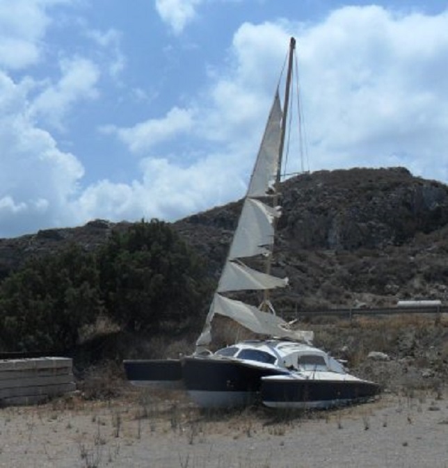Trimaran in deerniswekkende staat op de wal in Kissámos