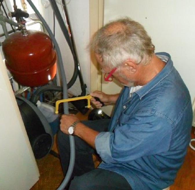 Op maat zagen van de nieuwe afvoerslang van de overstort van de CV-ketel