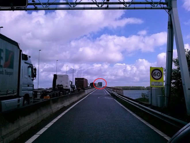 Het parallelweggetje over de Haringvlietbrug. Er is een storing, de brug wil niet meer dicht (rode cirkel), en dus een lange file op de A29 naast ons.